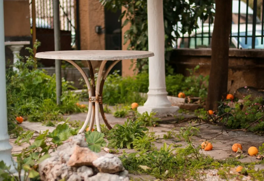 Table ronde en métal dans un jardin avec oranges tombées, Rome