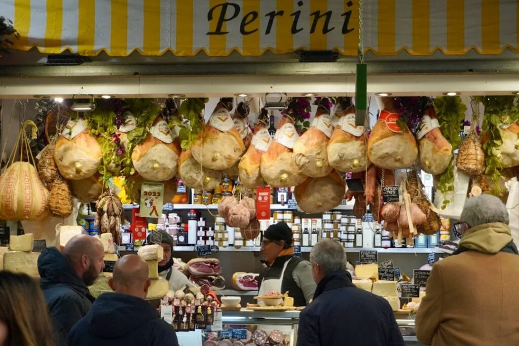 Étal de charcuterie à Rome au marché, jambons suspendus et clients