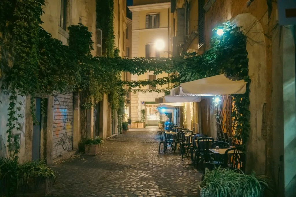 Terrasse extérieure éclairée dans une rue pavée de Rome, murs couverts de lierre