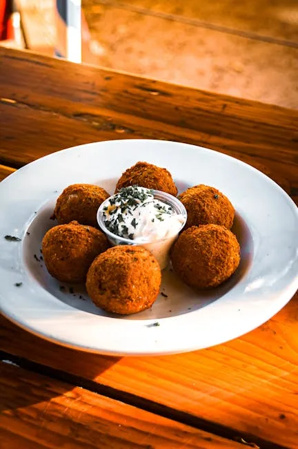 six boulettes frites disposées autour d'une sauce blanche sur assiette