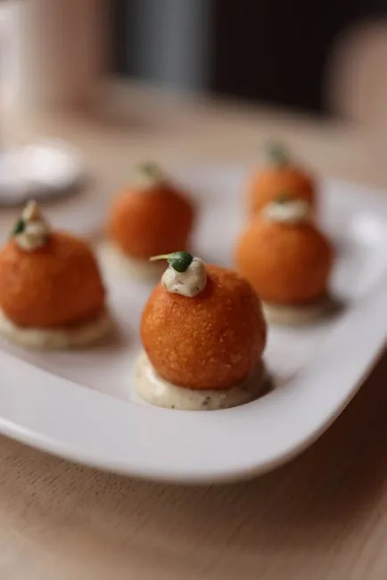 Petits supplì servis en amuse-bouche avec crème et câpre sur assiette