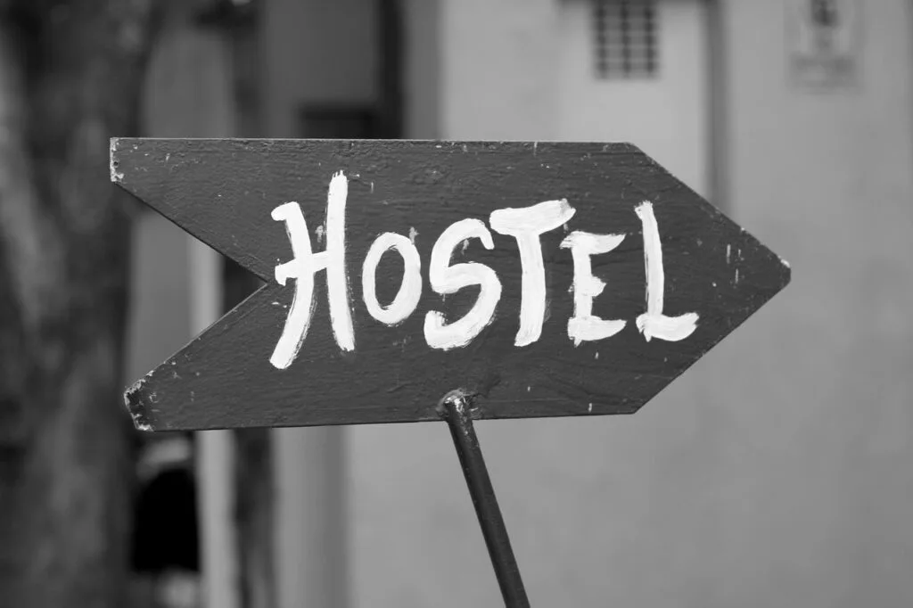 Panneau flèche 'HOSTEL' peint à la main indiquant une auberge à Rome