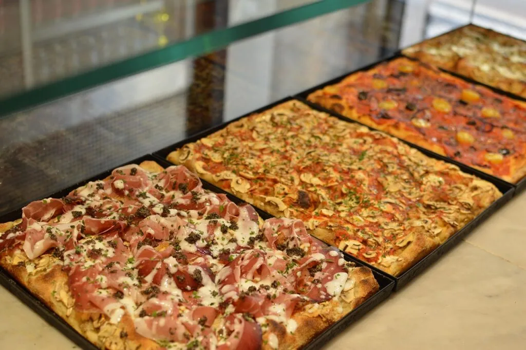 Grandes parts de pizza al taglio garnies de jambon et champignons à Rome
