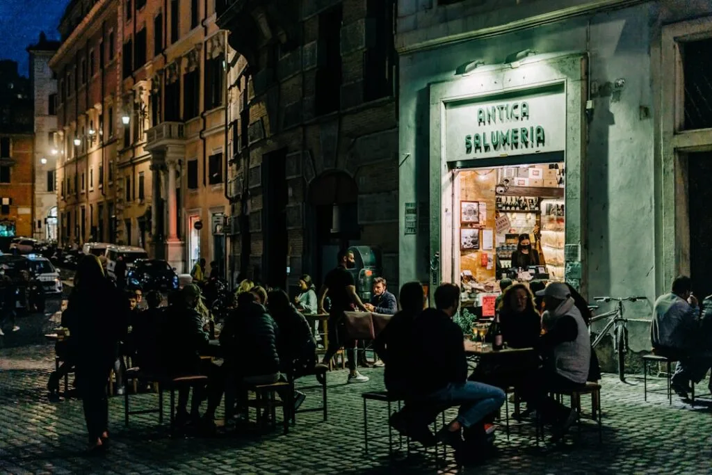 Clients attablés sur la place devant l'antica salumeria éclairée à Rome