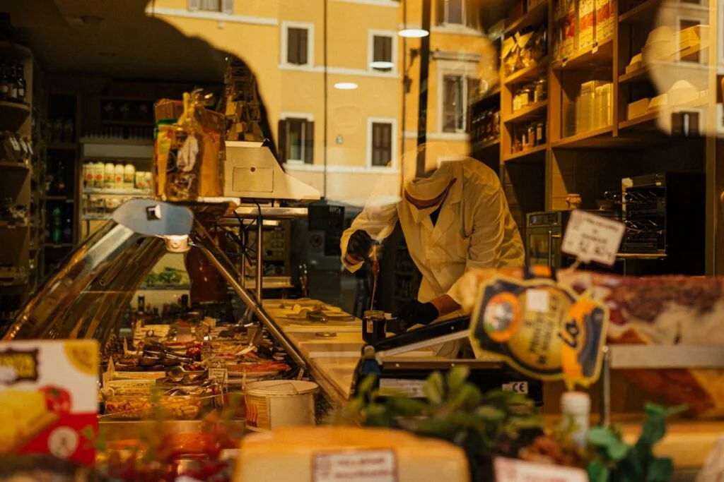 Vitrine d'une charcuterie romaine avec artisan en blouse coupant de la viande