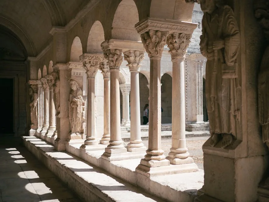 Cloître roman avec colonnes et chapiteaux sculptés, rayons de lumière