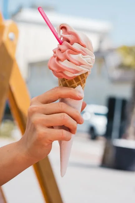 main féminine tenant une glace en cornet, rue pavée en arrière-plan