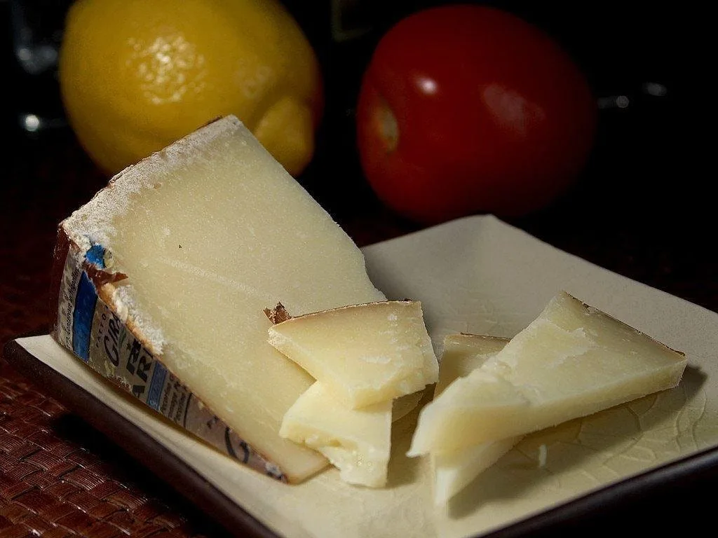 Morceau de pecorino sur assiette, citron et tomate en arrière-plan
