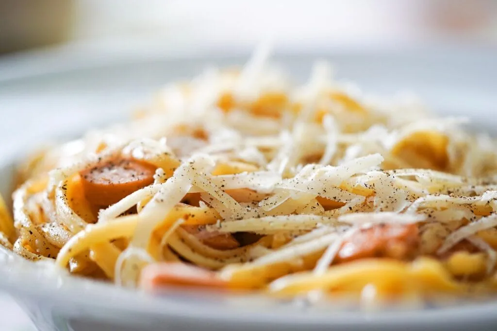 Gros plan sur des spaghettis saupoudrés de fromage et de poivre