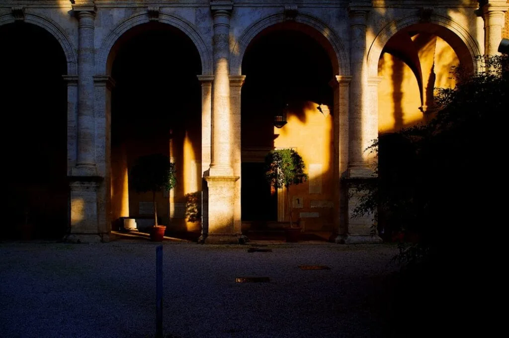 Arches de cloître baignées de lumière dorée dans un monastère romain