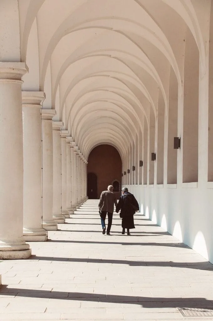 Couloir voûté du cloître d'un monastère romain, deux visiteurs main dans la main