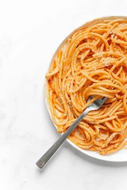 Assiette de pâtes à la sauce tomate orange avec une fourchette