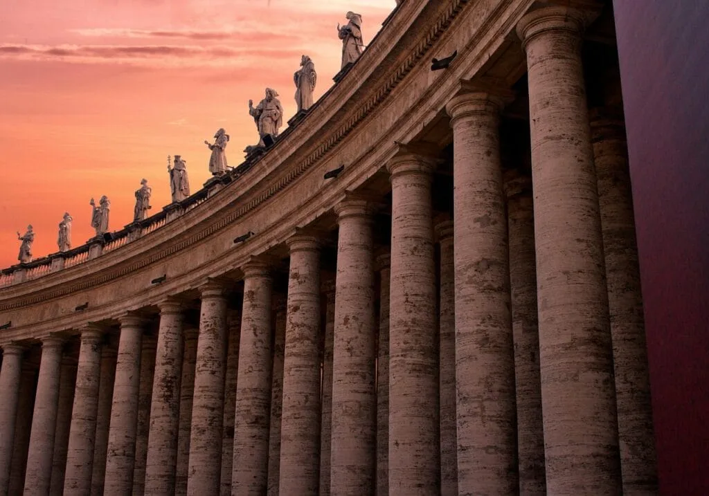 colonnade circulaire de la place Saint‑Pierre avec statues au coucher