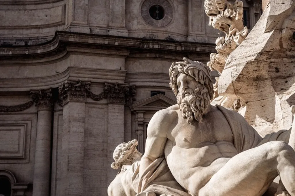 Gros plan sur une statue de marbre devant une façade baroque à Rome