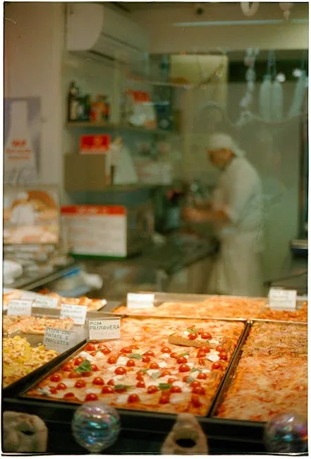 Comptoir de pizzas en tranches avec pizzaiolo flou en arrière-plan à Rome