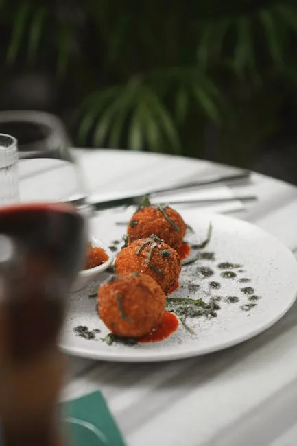 Trois supplì dorés servis sur assiette blanche, sauce tomate et verre de vin à Rome