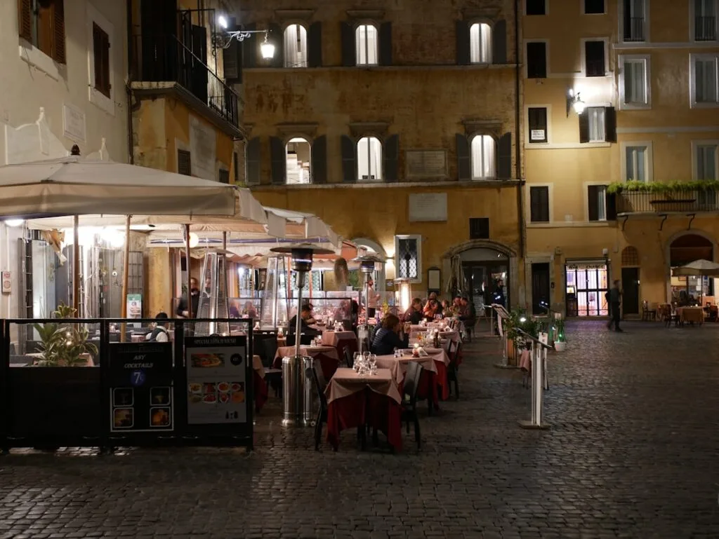 Terrasse de restaurant éclairée sur une place pavée de Rome