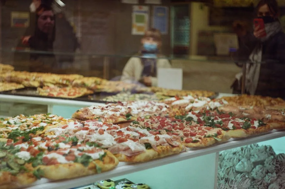 Plusieurs clients regardant le présentoir à pizzas al taglio