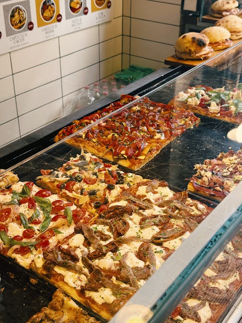 Comptoir vitré montrant pizzas al taglio rectangulaires et pains